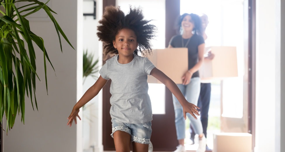 Parents entering new home with kid running in hallway